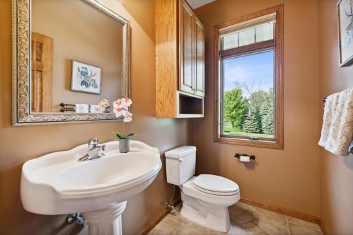 The half bathroom has ceramic tile floors, a pedestal sink, oak cabinets and oil rubbed bronze fixtures.