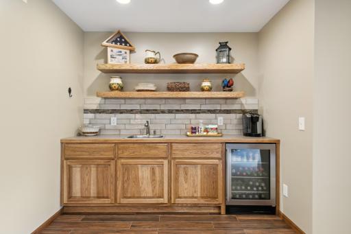 The wet bar has tile flooring, a tile back splash, solid hickory cabinets, a beverage refrigerator and the floating shelves are included too!