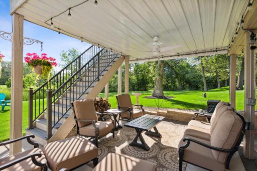 The covered patio space has a water management system, ceiling fan, remote controlled string lights, and a retractable shade.