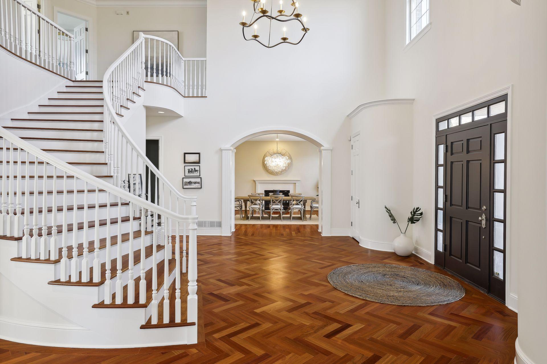 The front door opens to reveal a curved grand staircase.