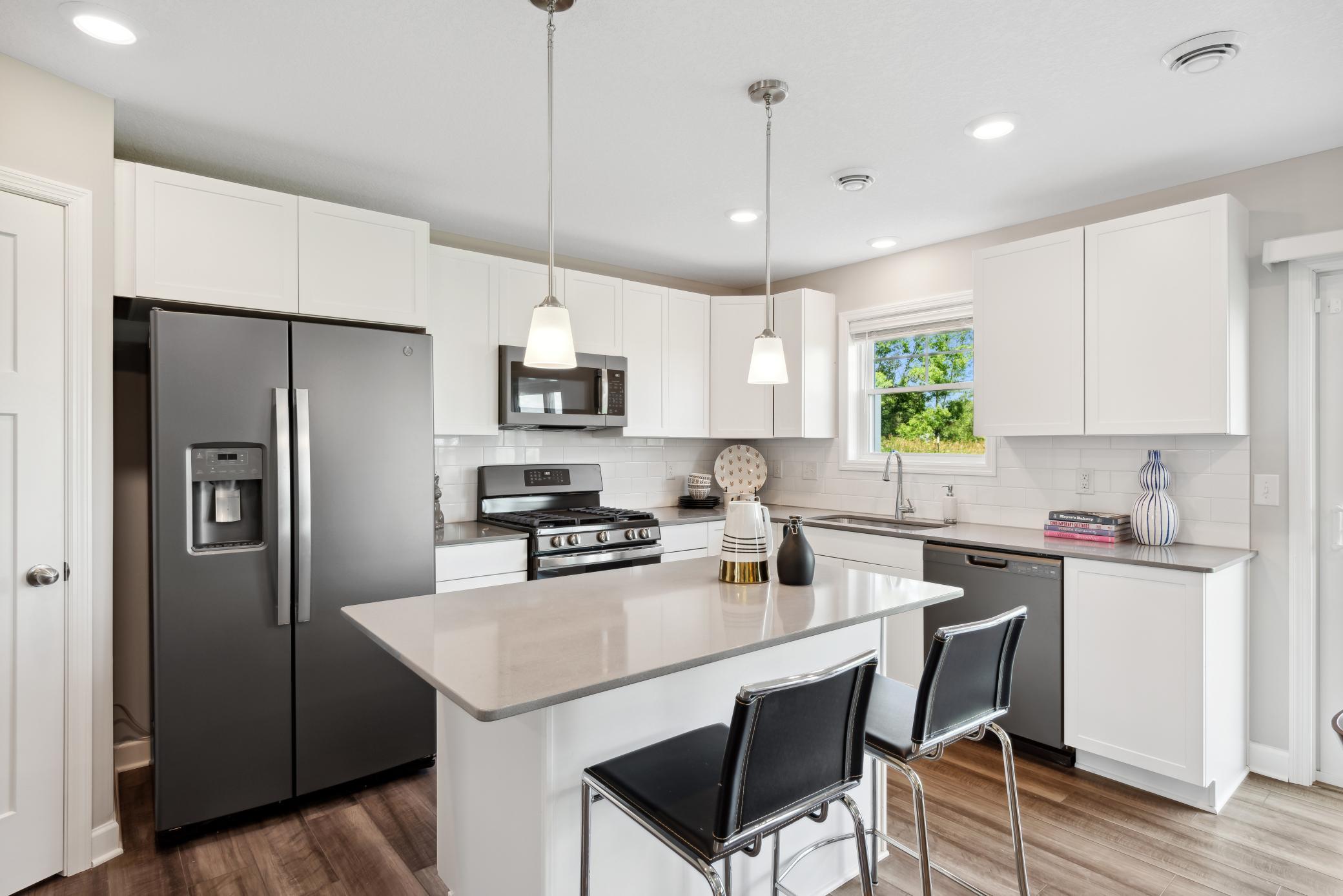 The beautiful kitchen has sleek white cabinets, slate finish GE appliances, luxury vinyl planking, tons of lighting and natural light as well as an island and a walk in pantry! *Please note, photos are of a model and are not the actual home.