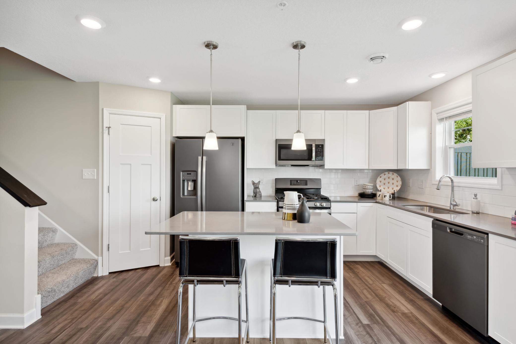 The beautiful kitchen features quartz countertops, white subway tile backsplash & pendant lighting. The island has seating for two & the pantry is in the corner. *Note, photos are of a model, not of actual home.