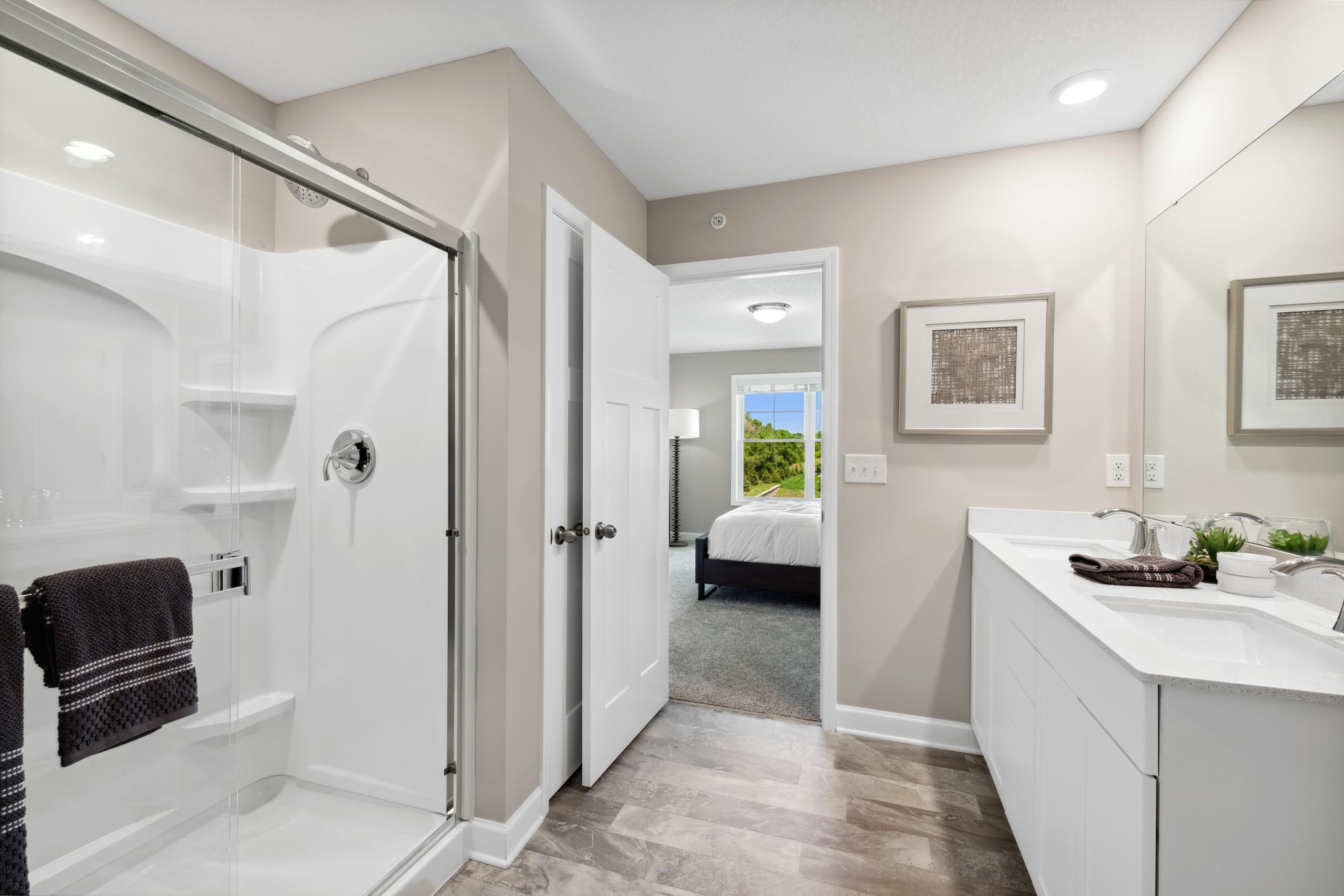 The spacious owner's ensuite bath features a double sink vanity with plenty of storage, a linen closet, and a shower. *Please note, photos are of a model and are not the actual home, but very similar.