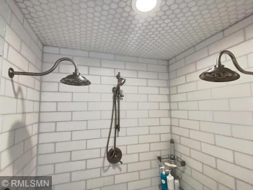 Subway tile surrounds the walk-in shower, with three shower heads and built in seat.