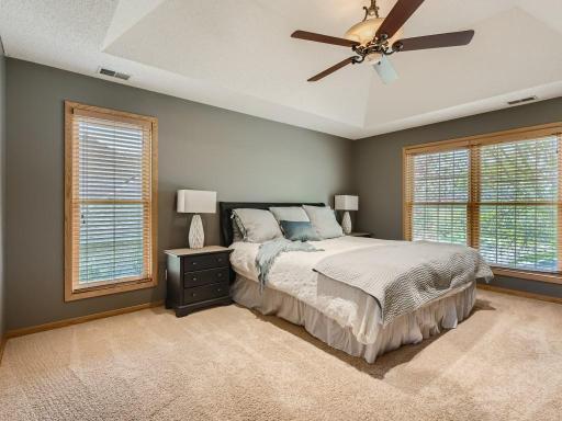A spacious primary bedroom with floor-to-ceiling windows and tray ceilings.
