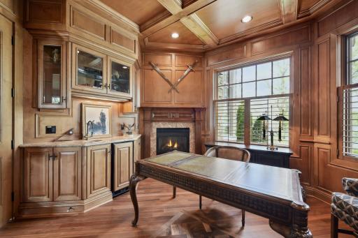 Office features a fireplace, wet bar, mini fridge, & immaculate woodwork and flooring