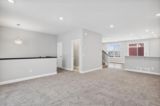 Family room with a powder room and open floorplan to kithcen and dining room. Photos not of actual home. Actual home will be similar floorplan; some colors and features may vary.