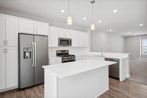 Upgraded white cabinetry, quartz countertops and slate appliances with a gas range. Photos not of actual home. Actual home will be similar floorplan; some colors and features may vary.