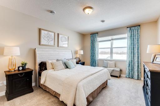 Primary bedroom with private en suite and walk-in closets has space for all of your bedroom furniture needs. Staged model photos. See listing agent for home specific selections.