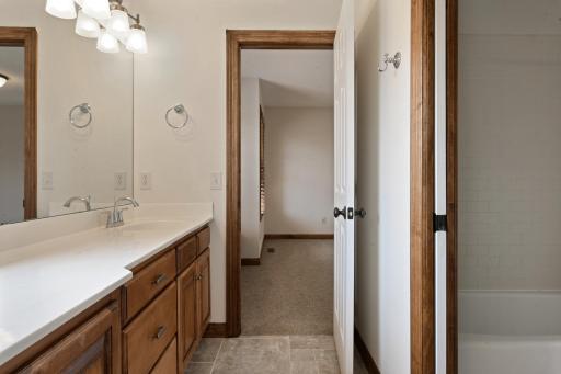Two-room walk-thru bath with dual vanity and tub/shower with subway tile surround