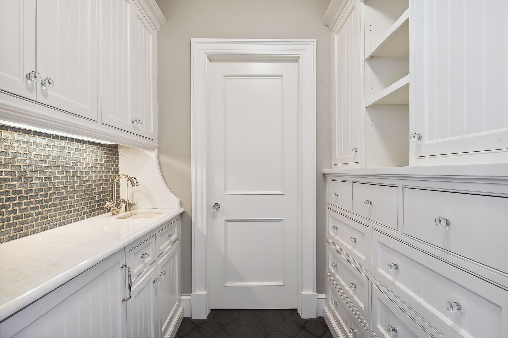 Separating the Primary Suite from the Primary Bathroom is a wet bar with a SubZero beverage refrigerator and reverse osmosis water tap, and floor-to-ceiling linen drawers and cabinets. The space also provides access to separate walk-in closets.