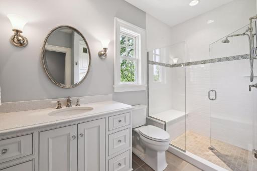 This en suite bath features a spacious, tiled shower and furniture-style vanity.