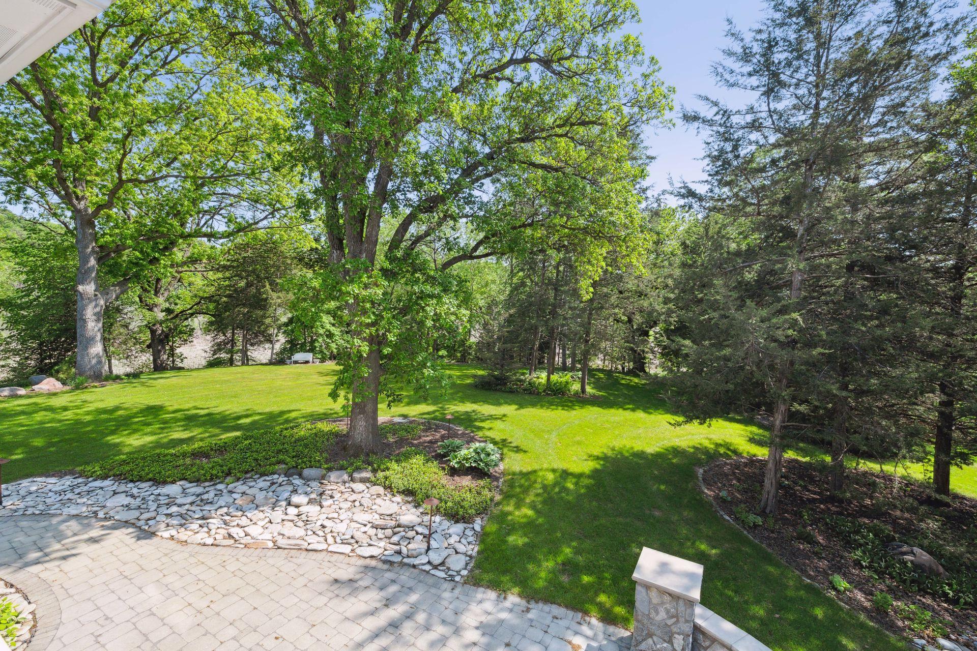 Extensive professional landscaping encircles the home and offers custom paver patios, well-manicured shrubs and towering trees.