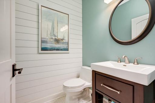 Main floor powder room with accent painted plank wall & mosaic floor tile.