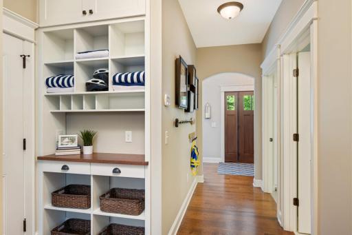 Back entry drop station with custom built cabinet, solid oak countertop, open shelving and electronic charging outlet. The door to the left opens to an oversized (30x34) 3 car garage. There is also a large walk-in coat closet at the end of this hall.