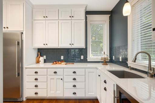 Abundance of quartz countertops for food prep, solid wood enameled custom cabinetry, glass tile backsplash, deep Blanco granite sink with motion sensor faucet & Insinkerator, full upright freezer.