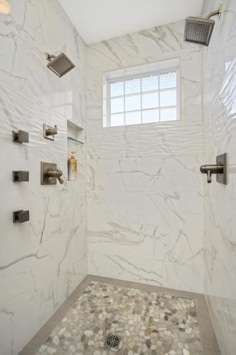You won't want to leave this walk-in shower (no doors to clean) featuring a pebble floor, floor to ceiling ceramic tile surround, 2 shower heads plus 3 body massage spa sprays!