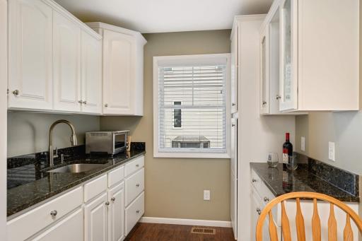 Close up view of the kitchenette. Notice the granite countertops, sink with Insinkerator and an abundance of cabinets.