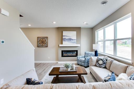 Soaring windows shed light on a main level living space that is large enough to handle most furniture set-ups and features a contemporary electric fireplace and mantle combination! (Photos of the same floorplan, colors will vary)