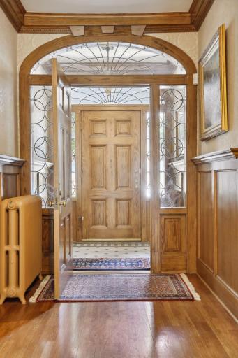 The foyer is enhanced with ceramic tile flooring, rich wood paneled walls, sidelight windows and a sunburst window.