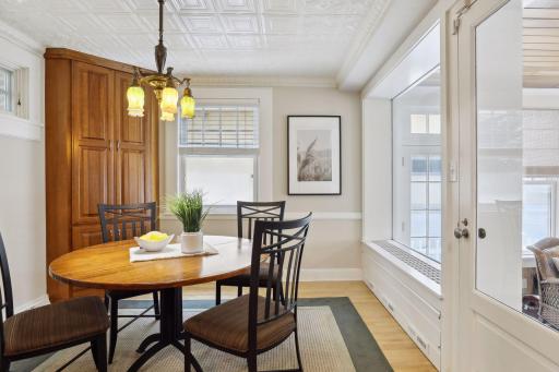 The eye-catching ceiling continues into the breakfast room, which has hardwood floors, a built-in corner cabinet, and door to the porch.
