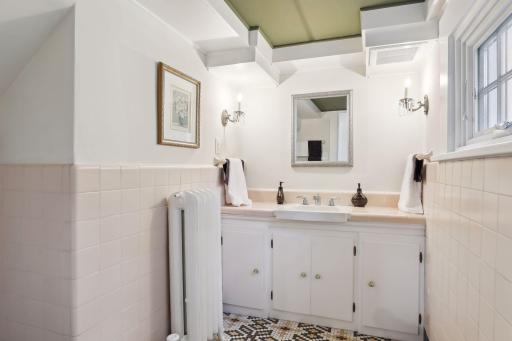 The office has a half bath with classic ceramic tile and a vanity for storage.