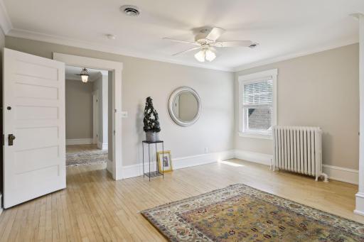 This bedroom is enhanced with hardwood floors and a ceiling fan.