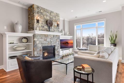 Gas fireplace with beautiful stone facade and surrounding built-ins help to anchor the living room