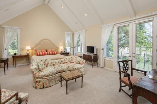 Main Floor Primary Bedroom with stunning vaulted ceilings and private balcony overlooking nature filled preserve