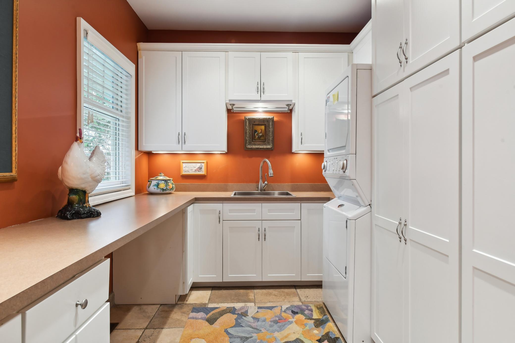 Well-appointed, the laundry room features heated tile flooring, great storage and folding counter space, as well as a utility sink.