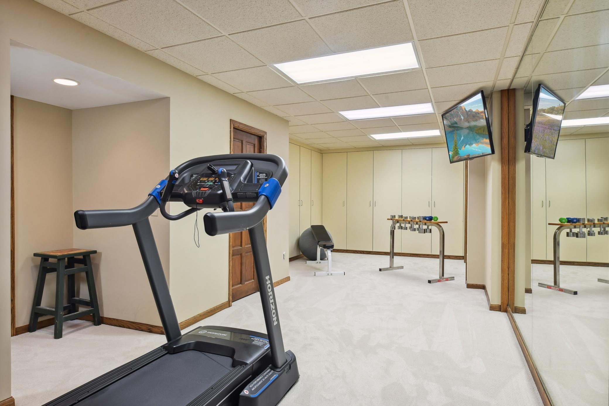 The exercise room, set off the amusement room, features a mirrored wall, television mount and access to mechanicals and storage areas.
