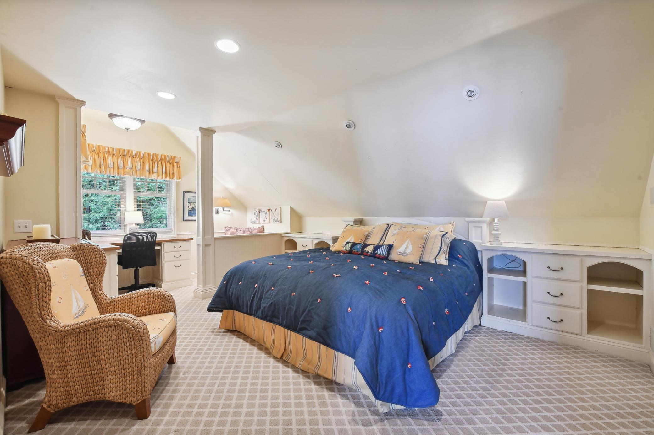 Bedroom 2 features a built-in headboard flanked with shelving and drawers, large wall closet with custom organizers and separate seating area.