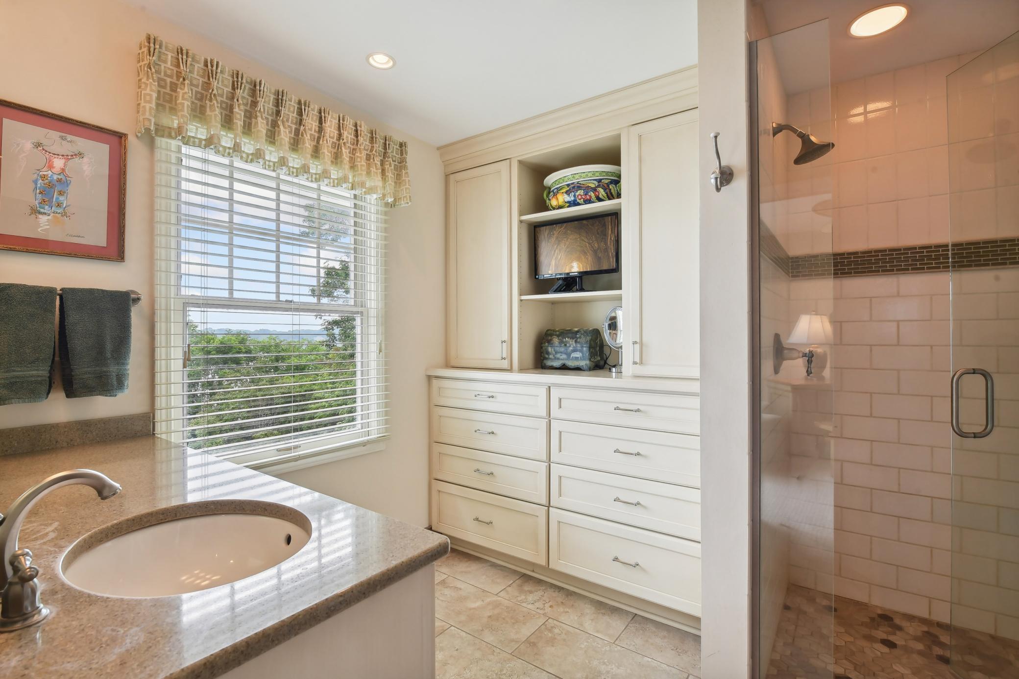 Nicely updated, the owners' bath features tile flooring, enameled vanity with granite counters, fabulous custom storage and tile surround shower stall with dual shower heads and a bench.