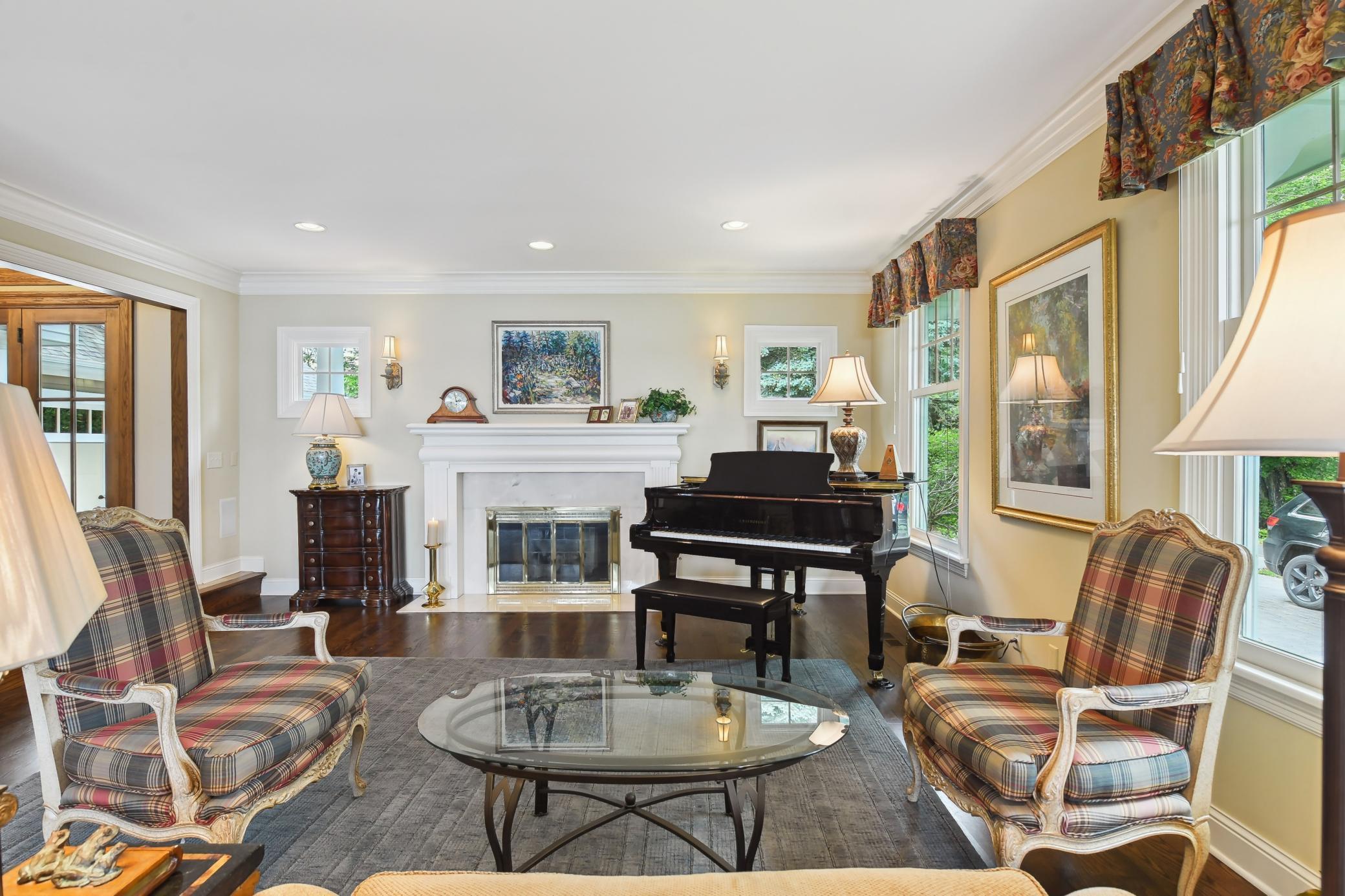 The formal living room is adorned with hardwood flooring, crown molding and fireplace