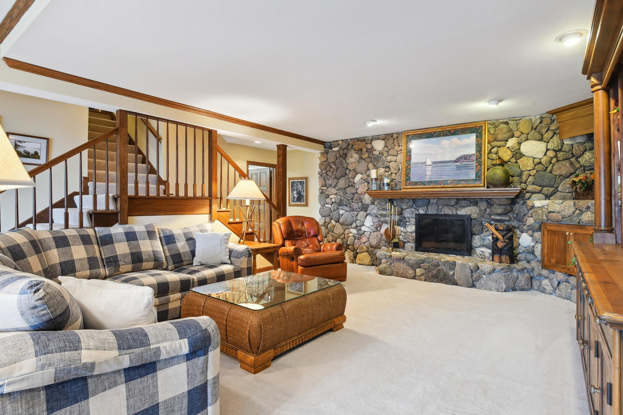 The walkout lower level offers an amusement room featuring a fireplace with stone surround and crown molding.