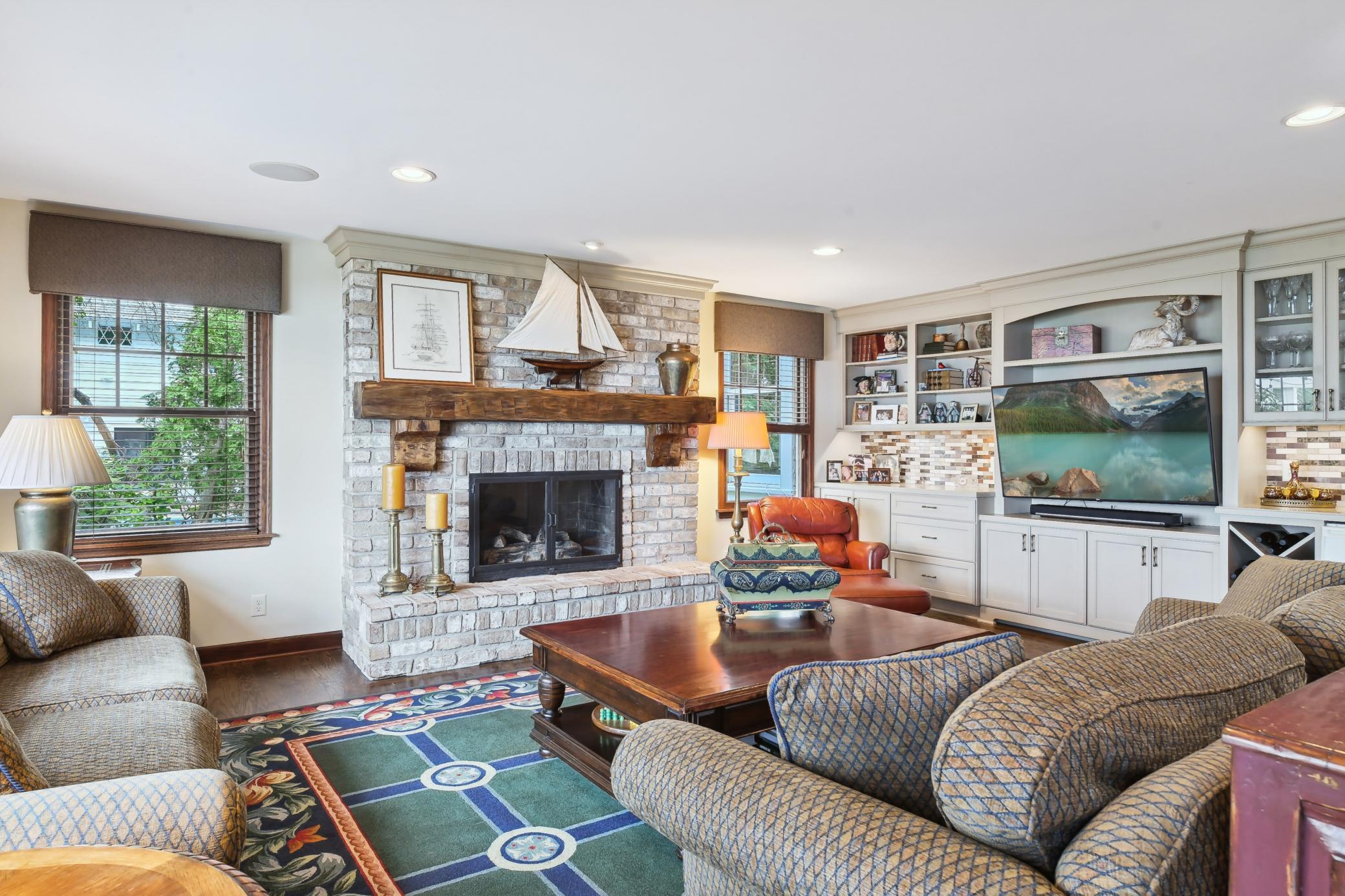 The family room showcases a floor-to-ceiling brick surround fireplace and a wall of built-in cabinetry offering great storage, beverage fridge and media center.