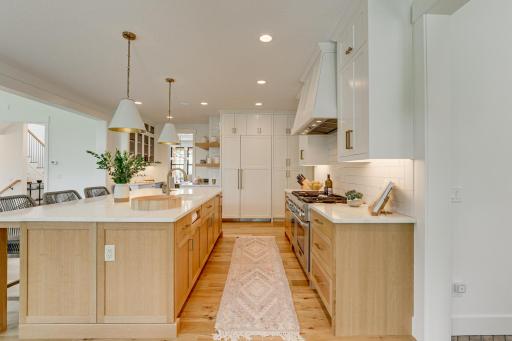 Photo of previously built home. Fantastic gourmet kitchen is equipped custom soft closed white oak cabinets accented with Top Knobs brushed brass and under cabinet lighting.
