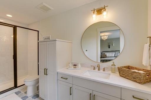 Photo of previously built home. Private 3/4 ensuite bathroom has a luxurious cement tile flooring, walk-in shower with glass doors and large single storage vanity with built-in linen cabinet.