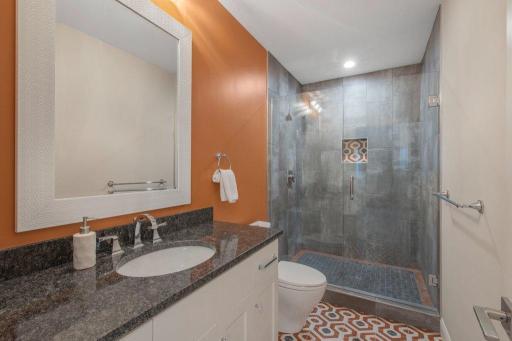 3/4 bath in lower level with glass & ceramic shower, granite topped vanity and tile floors.