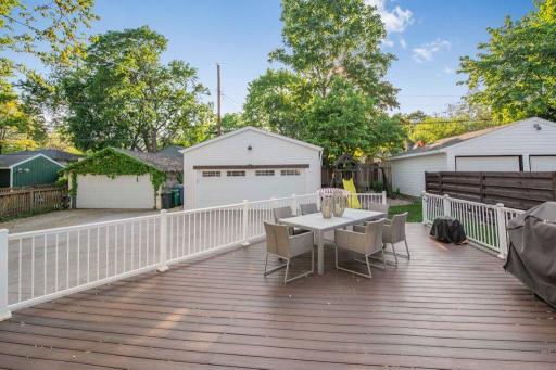 Massive and fully maintenance free deck to the rear of home steps out to a grassy area next to the two car garage.