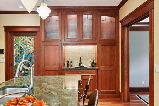 Built-in cabinet lighting and bar area with large pantry cabinets.