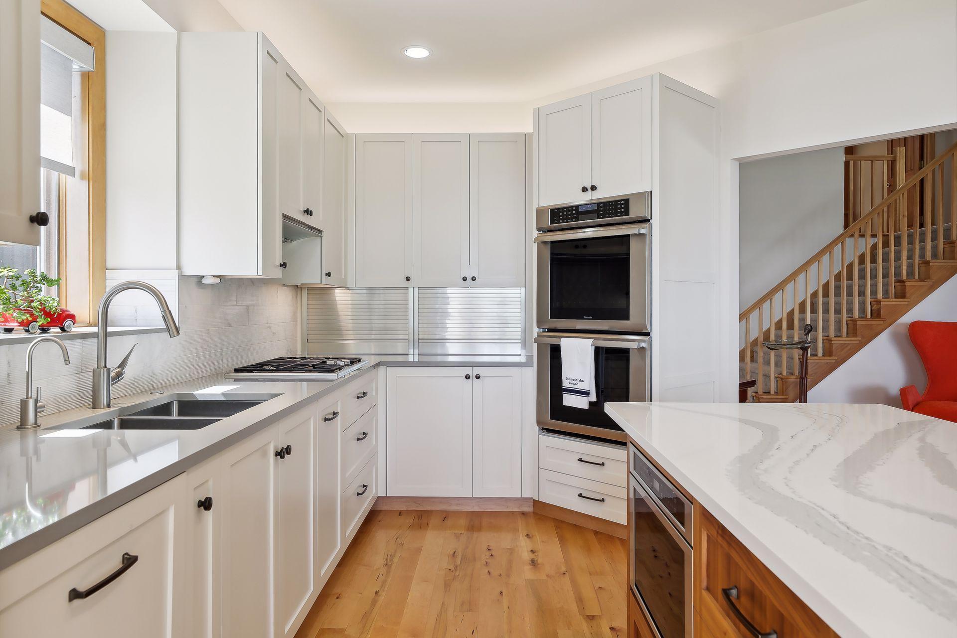 Crisp, enameled cabinetry, dual ovens + gas cooktop, quartz counters with tile backsplash