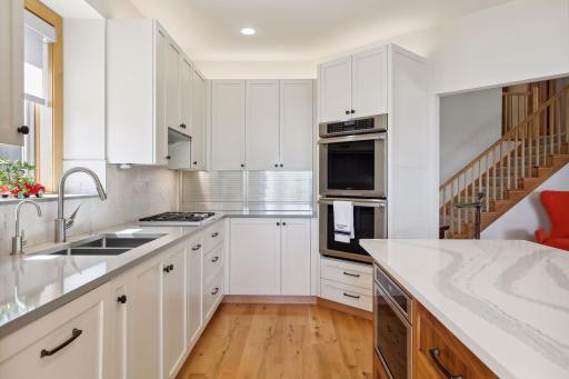 Crisp, enameled cabinetry, dual ovens + gas cooktop, quartz counters with tile backsplash