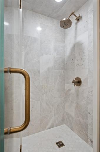 The stand-alone corner shower and gold fixtures enhance the modern and luxurious feel of the bathroom.
