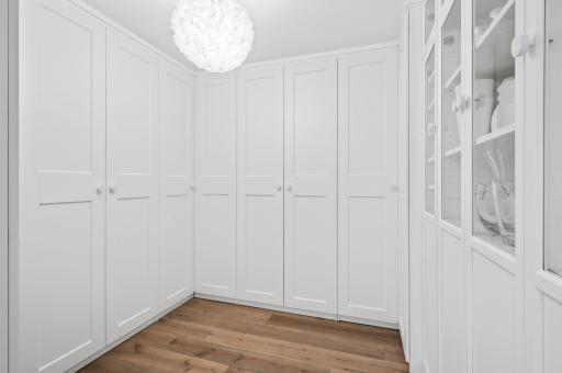 The bedroom has an attached walk-in closet that offers generous storage space. The closet is equipped with numerous built-in cabinets, providing ample room for organizing clothing, shoes, and accessories.