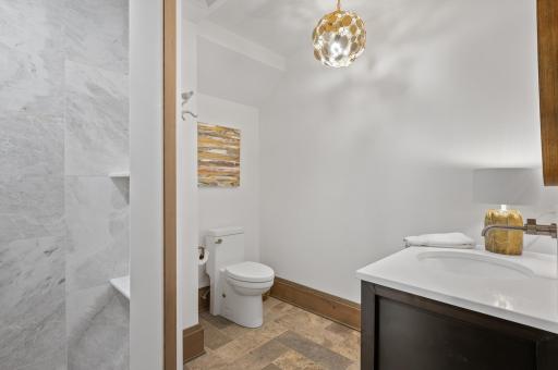 This lower-level bathroom combines the durability of tiled floors with the elegance of a built-in wood vanity and quartz top.