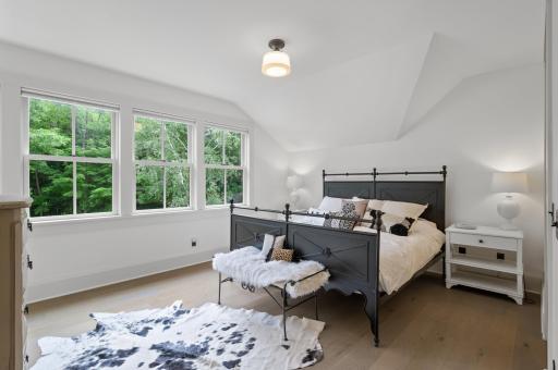 The owner's suite is adorned with four oversized windows, allowing natural light to flood the room and offering views of the surrounding landscape