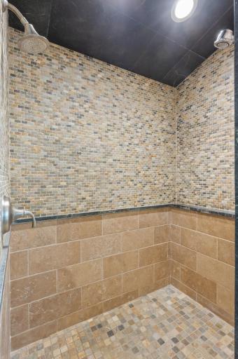 The bathroom includes a spacious walk-in shower equipped with three shower heads.