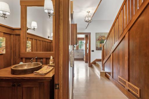 The main floor bathroom features a wood vanity that adds warmth and character to the room. It is complemented by a copper sink, which adds a touch of elegance and rustic charm.