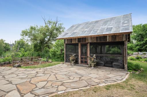 This custom-built outdoor living space combines the charm of a century-old barn frame with modern amenities, creating an inviting and visually stunning outdoor retreat.